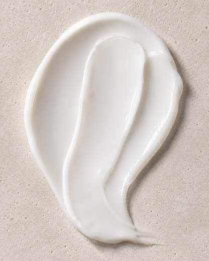 A thick, creamy white lotion smear on a textured beige stone surface.