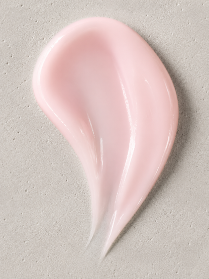 A smooth, glossy smear of pale pink cream or lotion on a textured light gray surface.